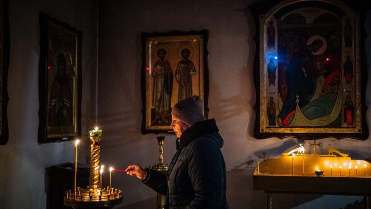 Une femme allume une bougie à Boutcha, près de Kiev, le 24 février 2023.
