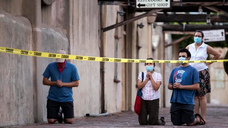 People praying next to the San Gabriel Mission after the historic church was severely damaged by a fire