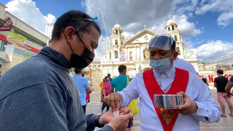 Heilige Eucharistie bei einer Freiluftmesse auf den Philippinen, im Hintergrund: eine katholische Kirche