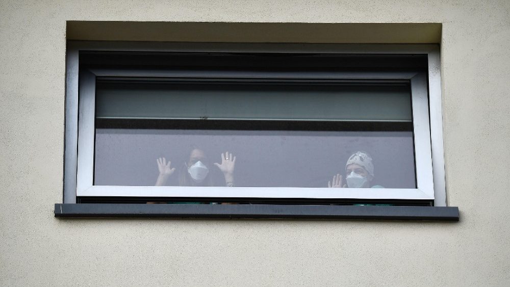 Enfermeiras e doentes acompanham oração das janelas dos hospital