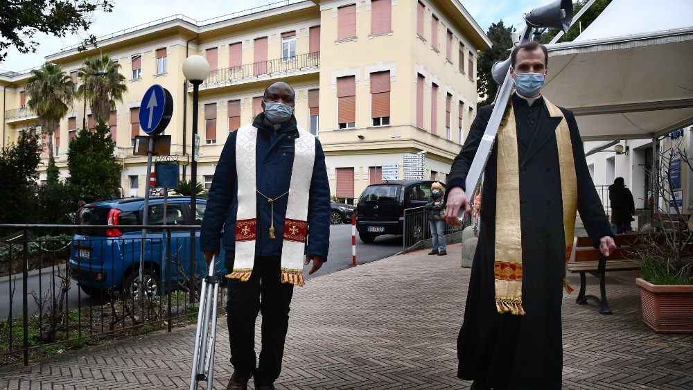 Os dois sacerdotes se deslocam com o megafone pelas vielas do hospital