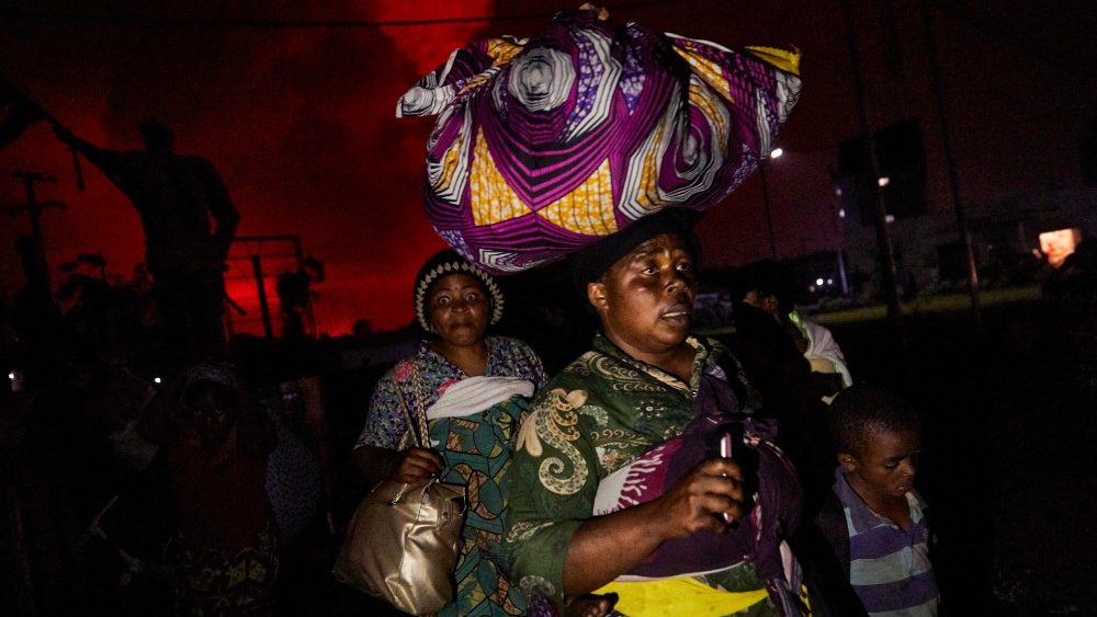 Uma mulher congolesa, carregando pertences na cabeça, foge do vulcão Monte Nyiragongo quando ele entra em erupção em Goma, República Democrática do Congo, 22 de maio de 2021. EPA/HUGH KINSELLA CUNNINGHAM