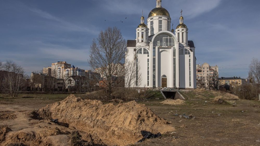  vala comum no jardim ao redor da igreja de Santo André em Bucha. (EPA/Roman Pilipey)