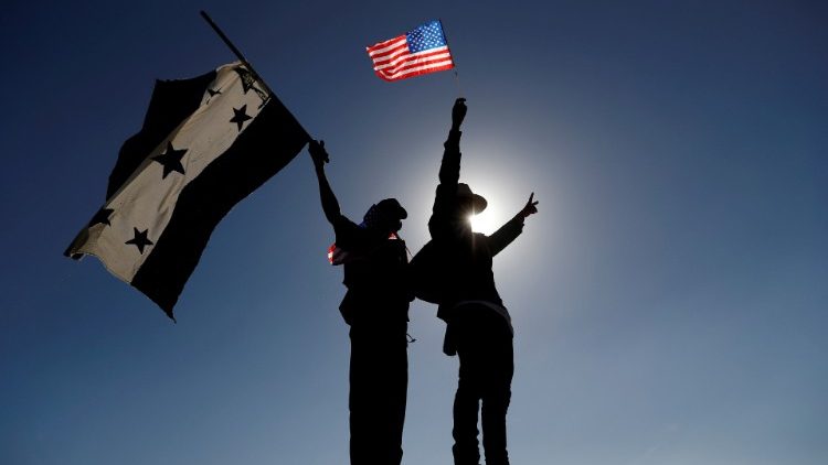 Migranten halten die Flaggen von Honduras und den USA hoch