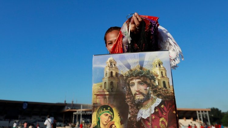 A woman sells posters to devotees waiting in line one day before the annual Black Nazarene procession, to touch the image, in Quiapo