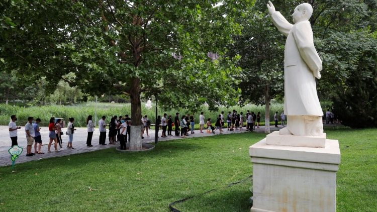 Menschenschlange vor einer Test-Station in Peking - rechts: eine Mao-Statue