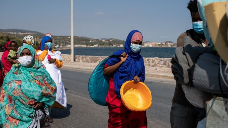 Refugees and migrants from the destroyed Moria camp carry their belongings as they walk towards a new temporary camp where they will be accommodated, on the island of Lesbos