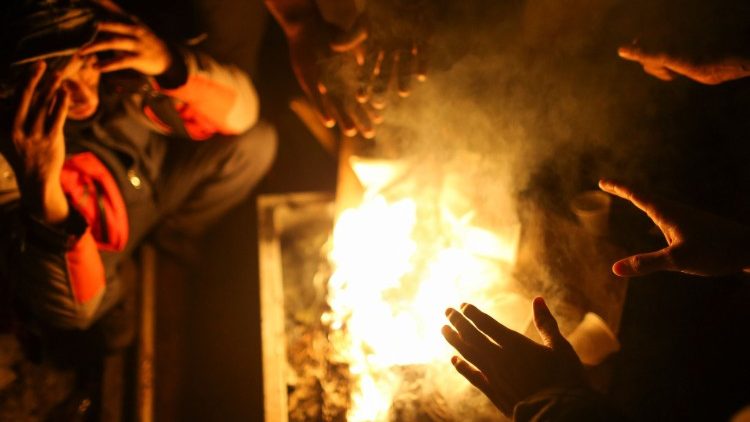 Migrants warm up around a fire at camp "Lipa" in Bosnia Herzegovina after it was destroyed by fire and closed