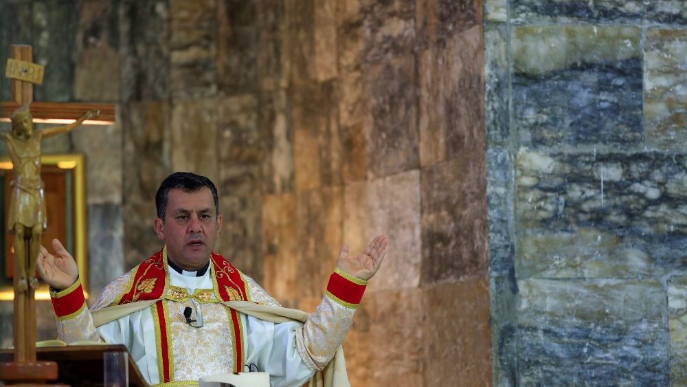 Padre Ammar Altony Yako, conduz as orações enquanto os cristãos iraquianos participam da Missa celebrada na velha igreja da Imaculada, em Qaraqosh