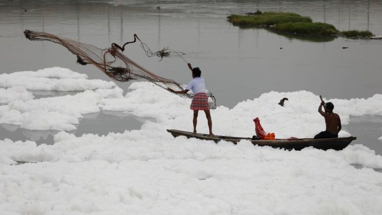 A man casts a fishing net into the polluted waters of the river Yamuna, New Delhi, India