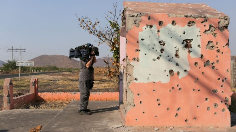 A cameraman films a bullet-ridden chapel in El Aguaje