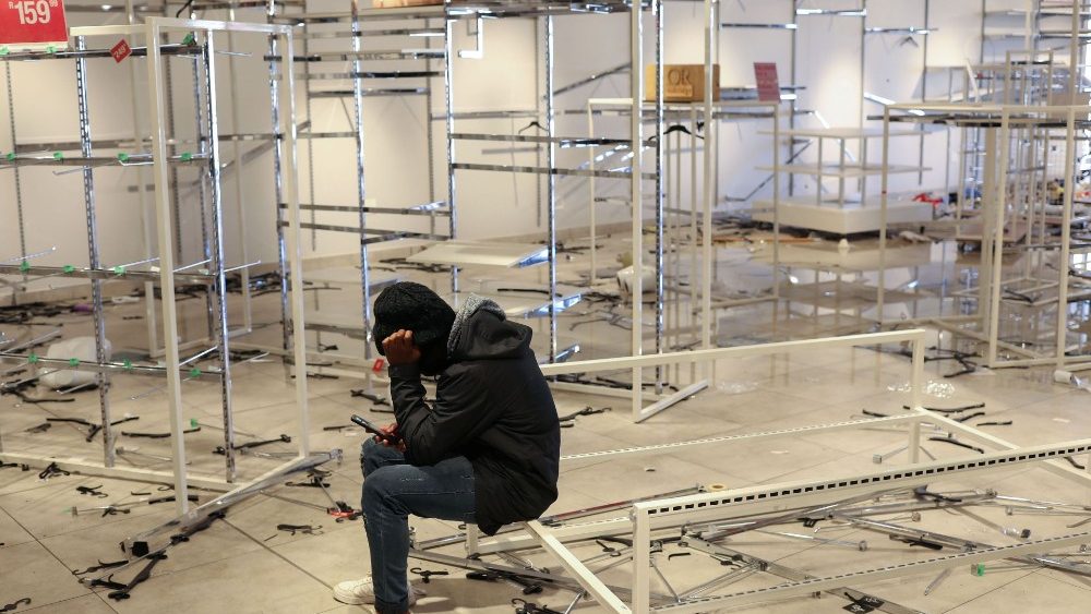 Um trabalhador usando seu telefone celular está sentado em uma loja saqueada enquanto o país envia o exército para conter os distúrbios ligados à prisão do ex-presidente Jacob Zuma, em Soweto. REUTERS / Siphiwe Sibeko