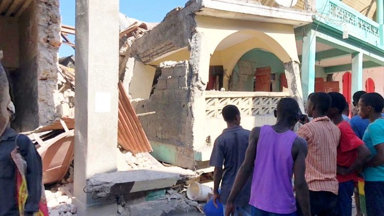 Pessoas  em frente a prédios desabados após terremoto em Jeremie