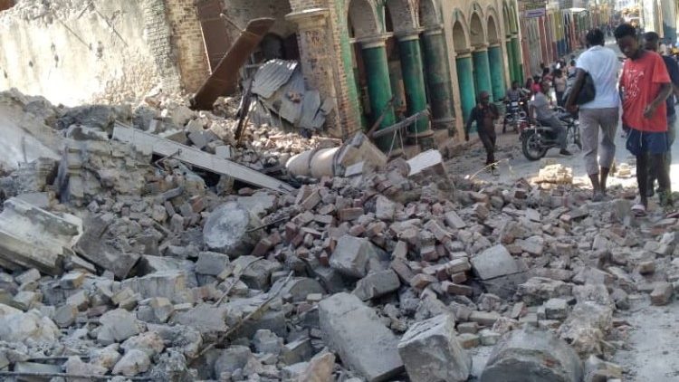 People walk next to debris following an earthquake in Jeremie