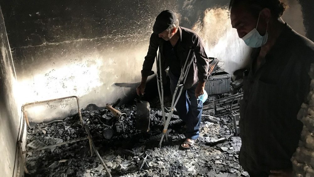 Lyazid Tazibt stands with his brother Khelaf inside their home that was burnt following a wildfire in the village of Ait Sid Ali