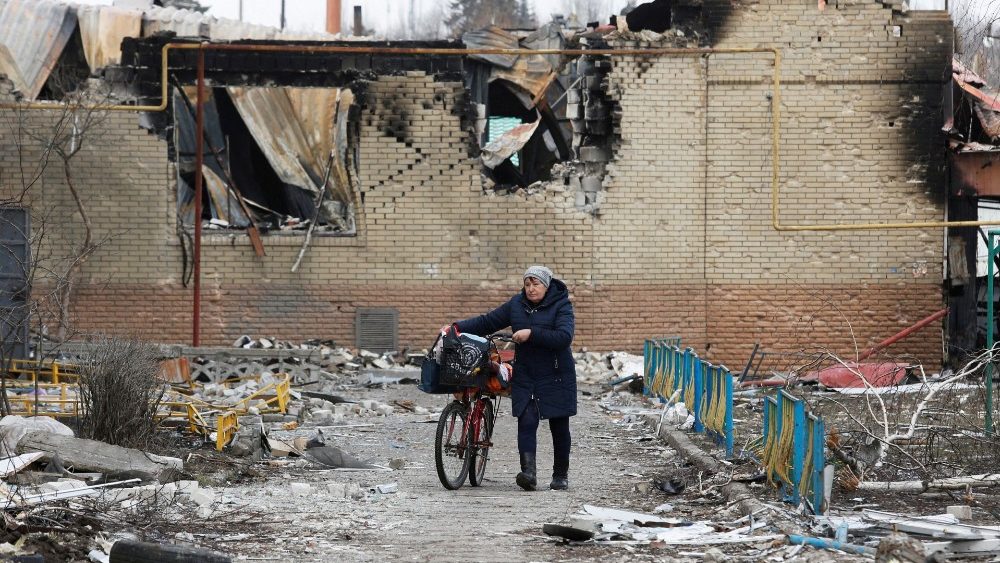 Uma mulher caminha com uma bicicleta ao lado de um prédio danificado durante o conflito Ucrânia-Rússia na cidade controlada pelos separatistas de Volnovakha, na região de Donetsk, Ucrânia. REUTERS/Alexander Ermochenko
