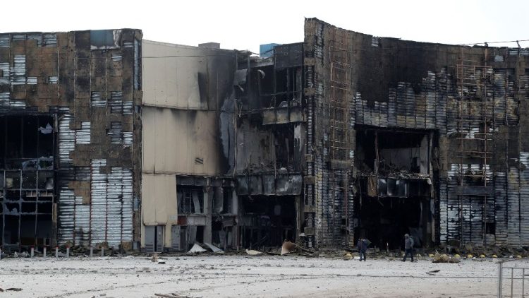 Pessoas caminham perto de um prédio, que foi destruído durante o conflito Ucrânia-Rússia na cidade portuária sitiada de Mariupol, Ucrânia, em 17 de março de 2022 REUTERS/Alexander Ermochenko
