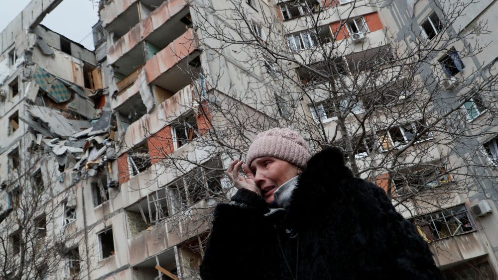 Uma mulher chora enquanto fala perto de um bloco de apartamentos, que foi destruído durante o conflito Ucrânia-Rússia na cidade portuária sitiada de Mariupol, na Ucrânia, em 17 de março de 2022. REUTERS/Alexander Ermochenko