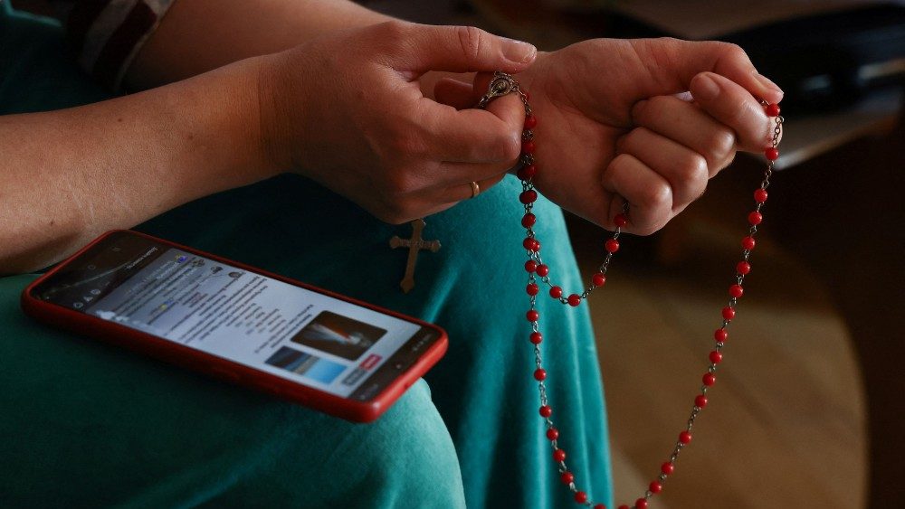 A ucraniana Vasilina, de 38 anos de Starychi, que fugiu da invasão russa da Ucrânia, reza o rosário usando o celular com uma oração ucraniana em uma casa do clero em Lubaczow, Polônia, em 21 de março de 2022. REUTERS/Kacper Pempel