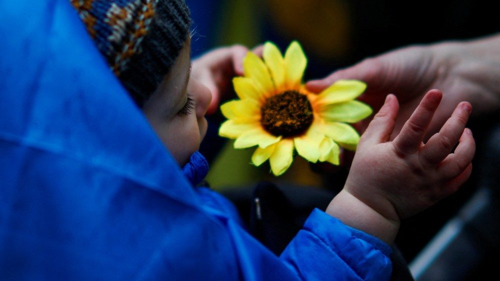Criança brinca com um girassol enquanto as pessoas participam da cerimônia em solidariedade ao povo ucraniano no Bowling Green Park em Manhattan, Nova York, REUTERS/Eduardo Muñoz