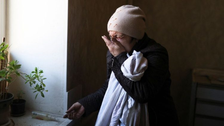 A Ukrainian woman cries as she waters a plant in her home in Mykolaiv