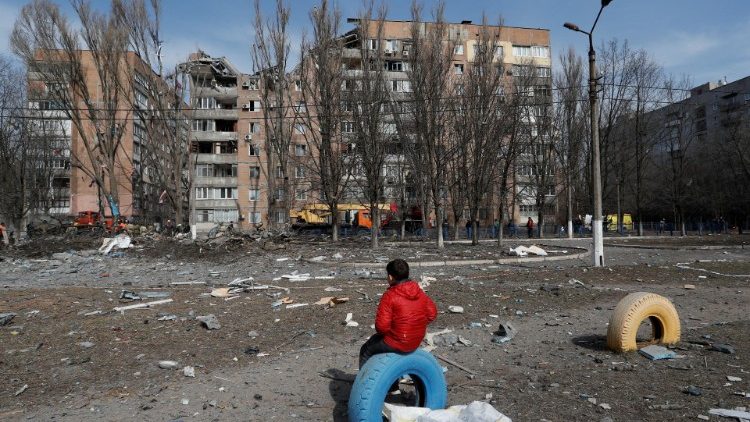 Um menino diante de um prédio das ruínas de um prédio bombardeado em Donetsk