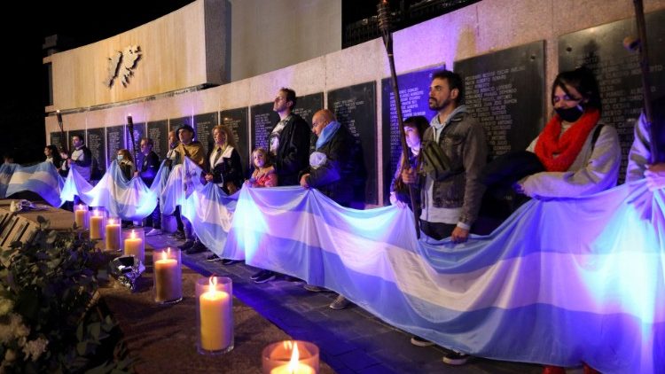 Argentinos sostienen la bandera frente al monumento dedicado a los fallecidos en la guerra de 1982 entre Gran Bretaña y Argentina.