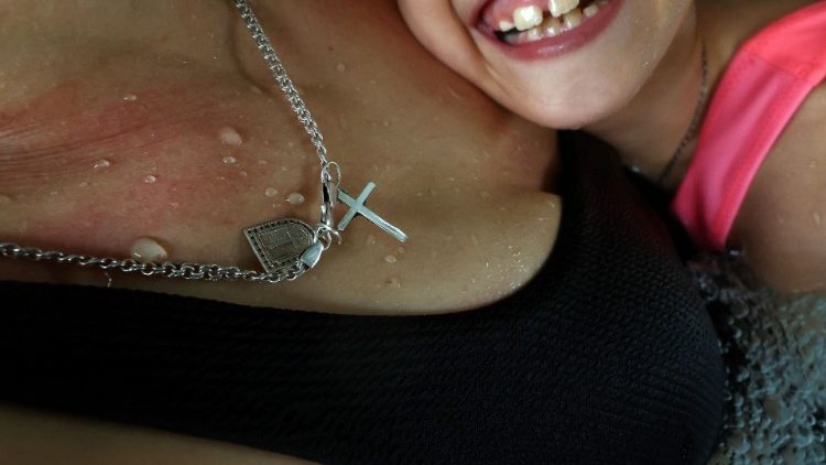 Um colar religioso está pendurado no pescoço da refugiada ucraniana Alexandra Zhuravel, 38, enquanto ela nada com sua filha Alevtina Bravorichenko-Crane, 8, na piscina do Centro Municipal de Esportes e Recreação, em Jaroslaw, Polônia, em 29 de março de 2022. "Alevtina ainda está com muito medo", disse Zhuravel. "Ela está sob constante estresse e tentamos distraí-la indo à piscina e fazendo caminhadas. Tentamos caminhar o máximo possível e brincar ao ar livre e pouco a pouco ela está conseguindo superar isso." REUTERS/Hannah McKay