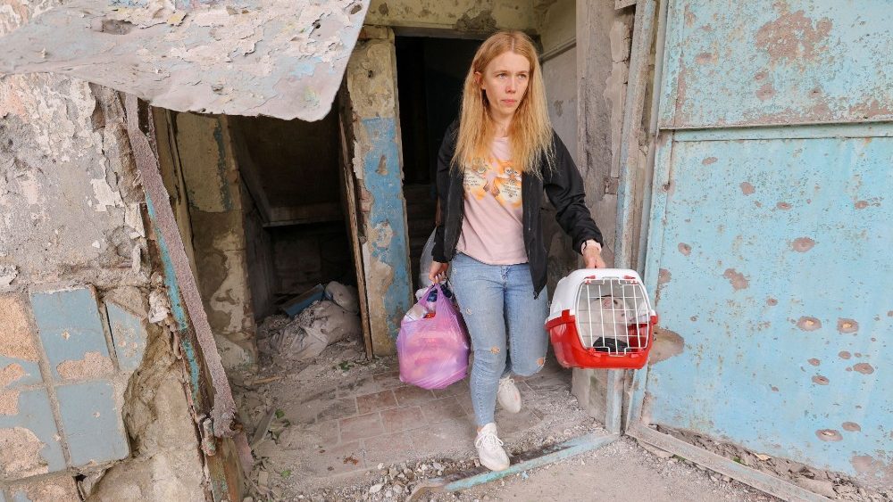 Pessoas carregam seus pertences e um gato ao deixar uma casa danificada após recente bombardeio no distrito de Petrovsky durante o conflito Ucrânia-Rússia em Donetsk, Ucrânia 25 de junho de 2022 REUTERS/Alexander Ermochenko