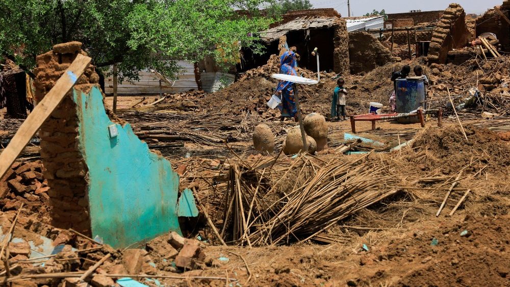 Familiares ficam nas ruínas de sua casa, na localidade de Al-Managil, durante enchentes no estado de Jazeera, Sudão, 23 de agosto de 2022. REUTERS/Mohamed Nureldin Abdallah