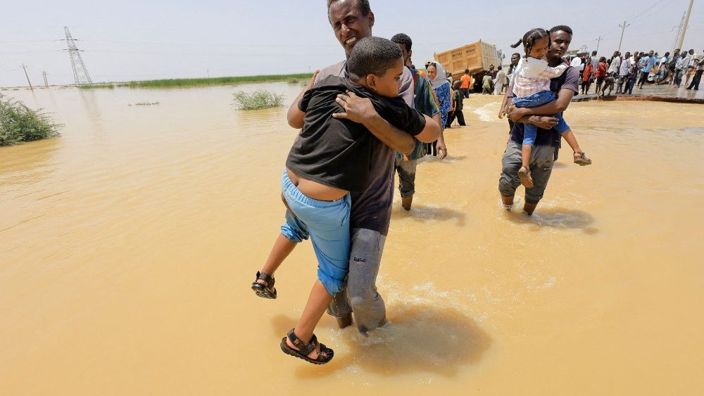 Pessoas atravessam a água durante uma enchente na localidade de Al-Managil, no estado de Gezira, Sudão, em 23 de agosto de 2022. REUTERS/Mohamed Nureldin Abdallah