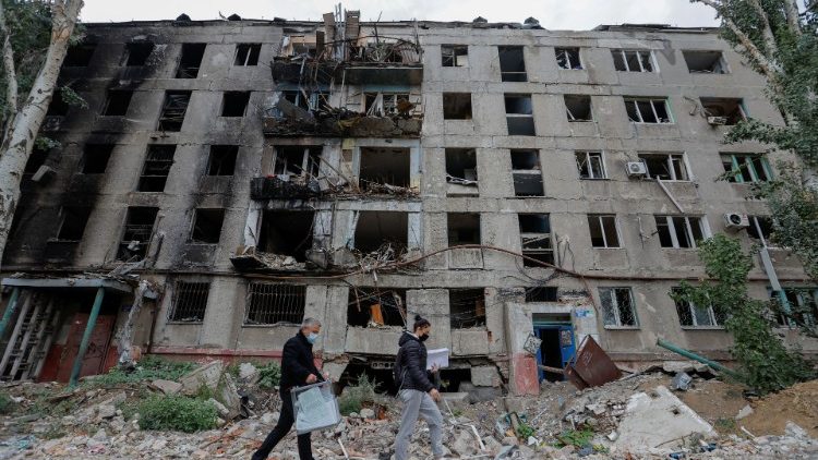 Membros de uma comissão eleitoral passam por um prédio destruído com uma urna móvel e documentos enquanto visitam moradores locais no segundo dia de um referendo sobre a adesão da autoproclamada República Popular de Donetsk (DPR) à Rússia, em Mariupol, Ucrânia, em setembro 24, 2022. REUTERS/Alexander Ermochenko