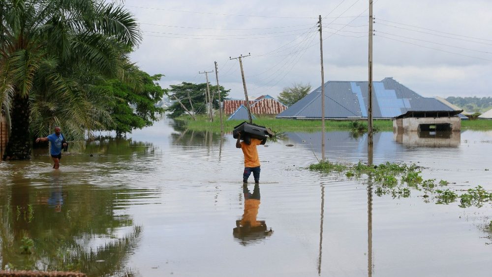 Um homem com uma caixa na cabeça atravessa uma enchente em Makurdi, Nigéria, em 1º de outubro de 2022. REUTERS/Afolabi Sotunde