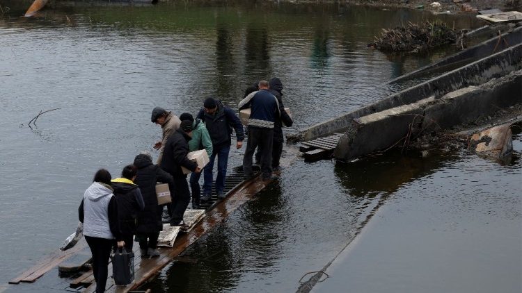 As pessoas saem e voltam para seus abrigos enquanto atravessam uma ponte destruída para coletar ajuda, enquanto a invasão russa da Ucrânia continua, na região leste de Donbas de Bakhmut, Ucrânia, 30 de outubro de 2022. REUTERS/Clodagh Kilcoyne