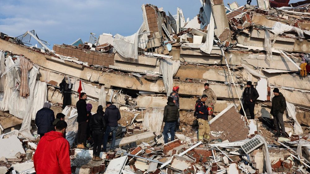 Pessoas observam a destruição enquanto equipes de resgate procuram sobreviventes nos escombros após um terremoto em Hatay, Turquia, 7 de fevereiro de 2023 REUTERS/Umit Bektas