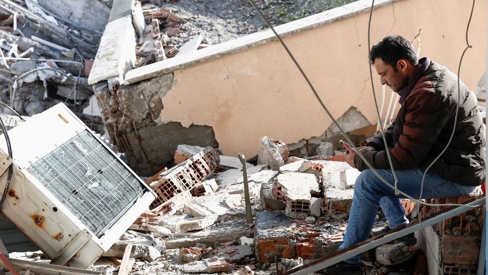 Uma pessoa senta-se no local da unidade de terapia intensiva do hospital estadual desmoronado de Iskenderun após um terremoto em Iskenderun, distrito de Hatay, Turquia, 7 de fevereiro de 2023. REUTERS/Benoit Tessier