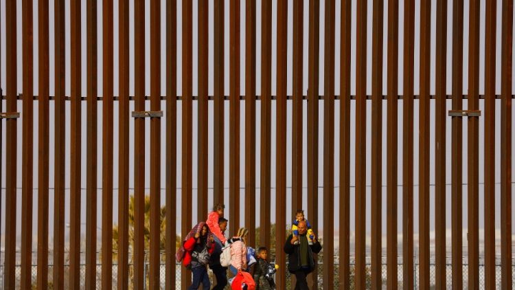 A Venezuelan family walks next to the border wall with the US after crossing the Rio Bravo river
