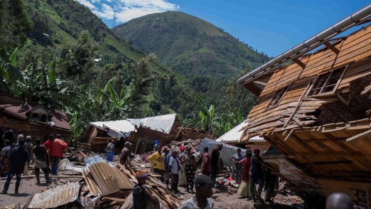 Residents in the village of Nyamukubi gather to search for loved ones buried under the mud.