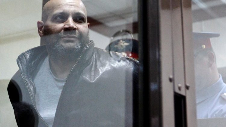 FILE PHOTO: Khadzhikurbanov is escorted into a glass-walled cage before a court hearing in Moscow