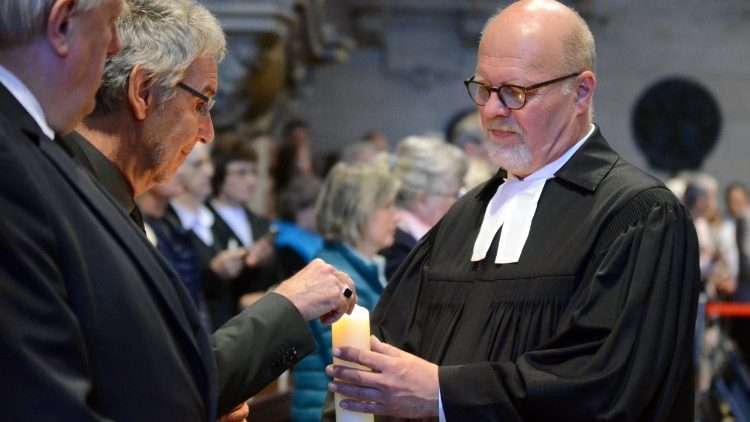 Superintendent Ulf Schlien gibt das Licht der Osterkerze an die im Dom Versammelten weiter