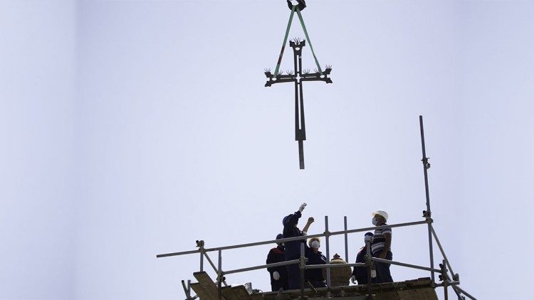 Ein Kirchturm empfängt sein frisch renoviertes Kreuz