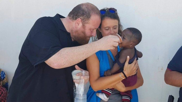 Don Carmelo La Magra con un piccolo migrante a Lampedusa