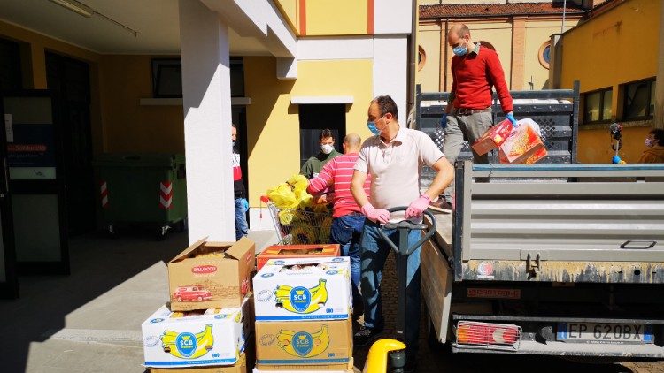 Volontari e operatori di Caritas Ambrosiana scaricano i prodotti per un Emporio della solidarietà