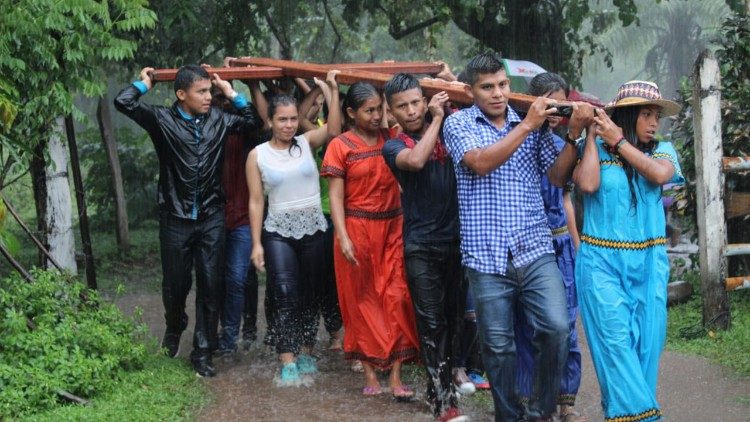 Jóvenes, miembros de pueblos originarios, cargan la cruz, bajo una lluvia torrencial