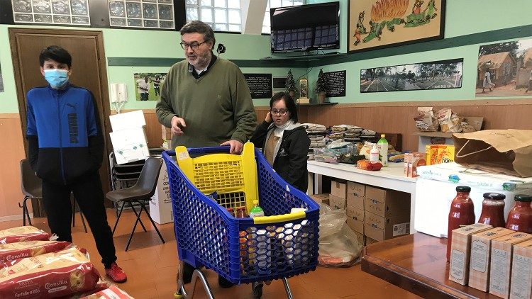 Dustin, don Luigi e Rita riempiono il carrello per una famiglia bisognosa con derrate non deperibili