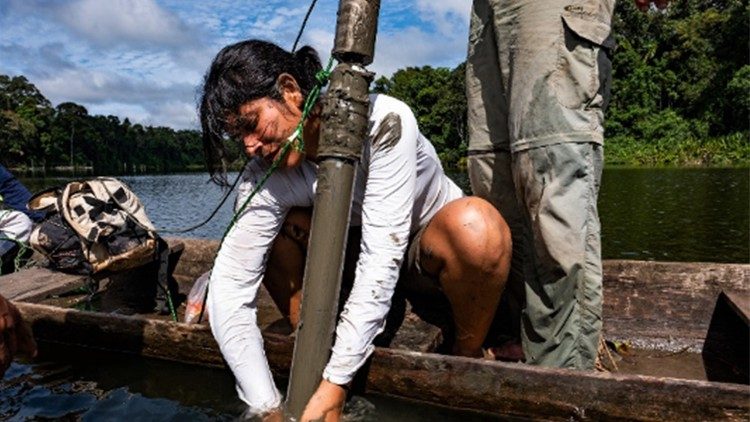 A cientista recolhe amostras de sedimentos nos rios