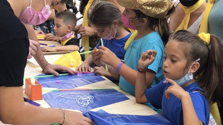 Bambini romani e rifugiati imparano a costruire un aquilone in Piazza San Pietro