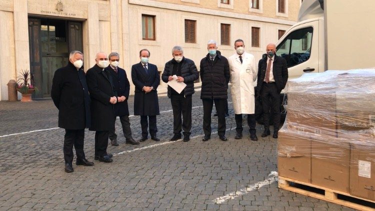 Foto di gruppo con uno dei bancali con i farmaci e i dispositivi medici essenziali. 