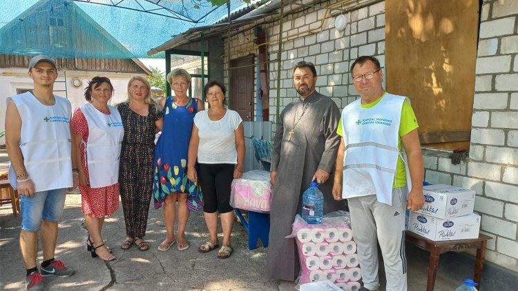 Sacerdote com sua equipe na distribuição das ajudas