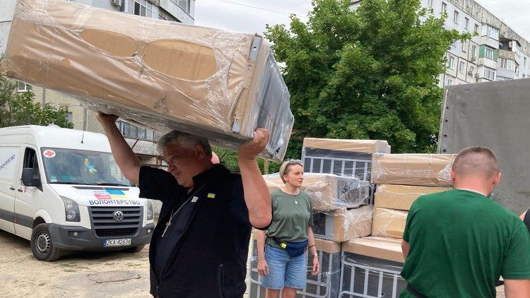 Kard. Krjewski  pomaga rozładować samochów z łóżkami dla powodzian